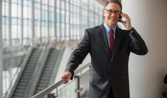 Mature businessman with glases calling by phone at the airport
